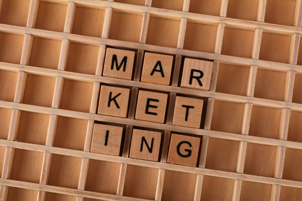 Wooden letter tiles arrange the word marketing on a grid backdrop, highlighting creativity and a business concept.